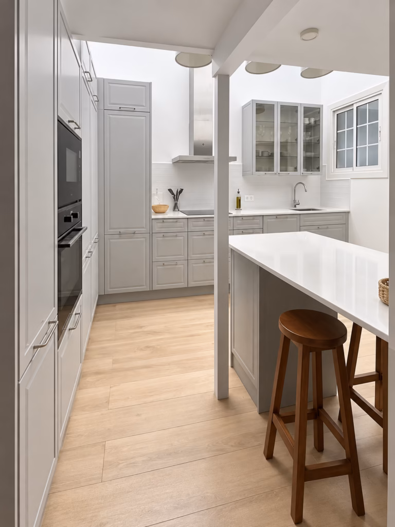Vista de la cocina de Casa Calvet hacia la barra, con taburetes y armarios altos