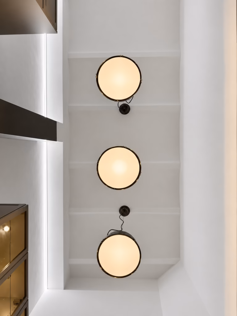 Vista hacia el techo de la cocina de Casa Calvet, con tres lámparas suspendidas e iluminación perimetral
