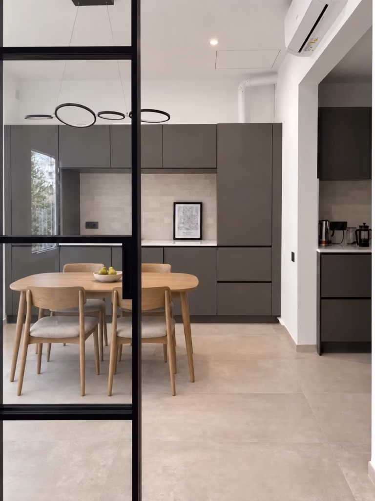 Cocina y comedor conectados por una carpintería acristalada negra