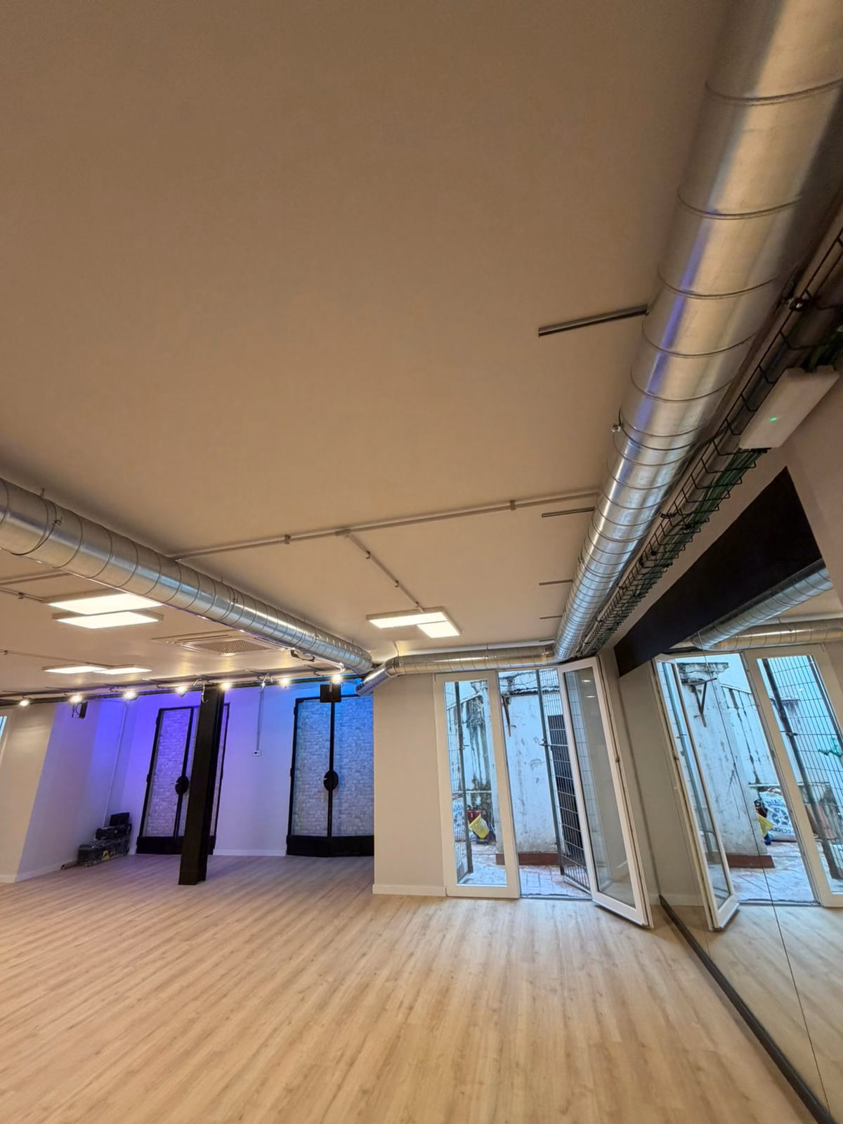 Conductos metálicos de extracción instalados a la vista en el techo de una sala de baile.