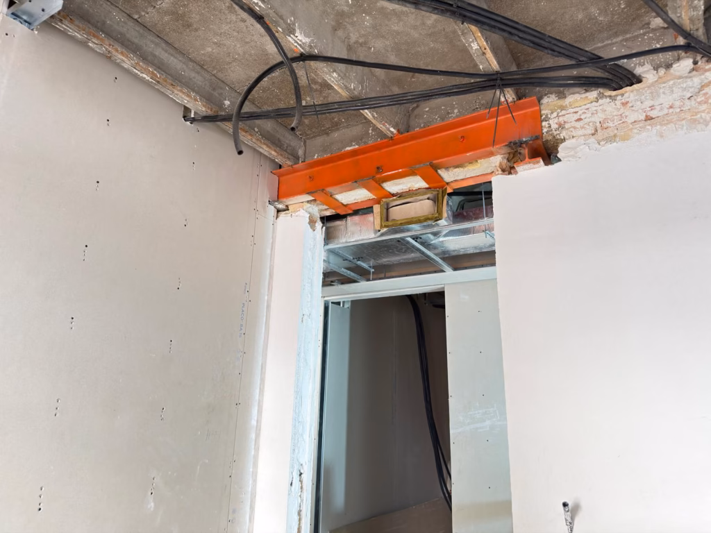Perfil metálico sobre un paso interior durante la reforma de una vivienda en Barcelona.